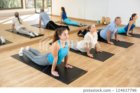 Girl doing Upward Facing Dog pose during group yoga workout 124637796