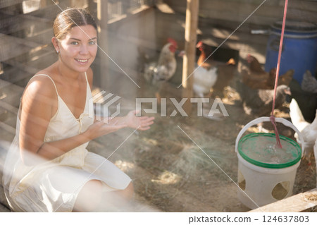 Young girl feeding hens and roosters in henhouse 124637803