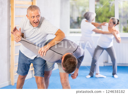 Old man twisting her opponent's arm during self-defense classes 124638182