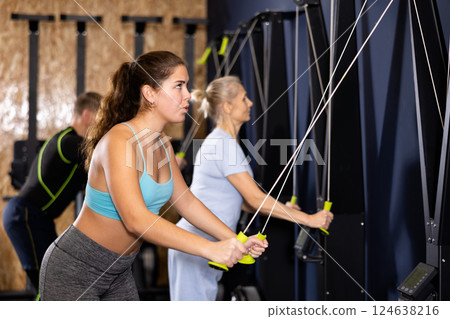 Girl exercising upper body muscles on ski machine in gym 124638216