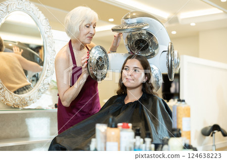 Professional female hairdresser doing volume haircut of an young woman in hairdressing salon Professional female hairdresser doing volume haircut of an young woman in hairdressing salon 124638223