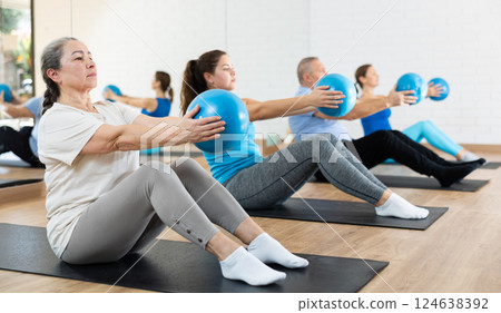 Elderly woman practicing pilates with ball in gym area Elderly woman practicing pilates with ball in gym area 124638392