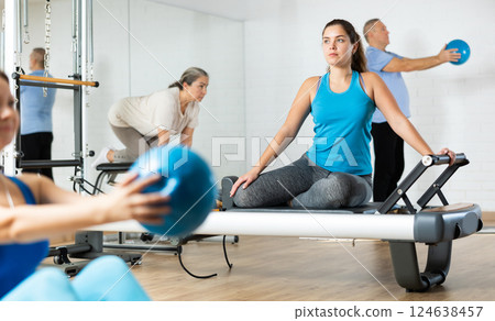 Young girl practicing pilates stretching exercises on reformer Young girl practicing pilates stretching exercises on reformer 124638457