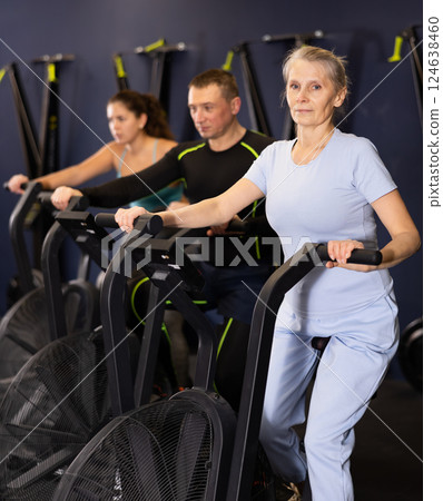 Group of people engaged in a spin bike simulator in the gym, exercising on stationary bike Group of people engaged in a spin bike simulator in the gym, exercising on stationary bike 124638460