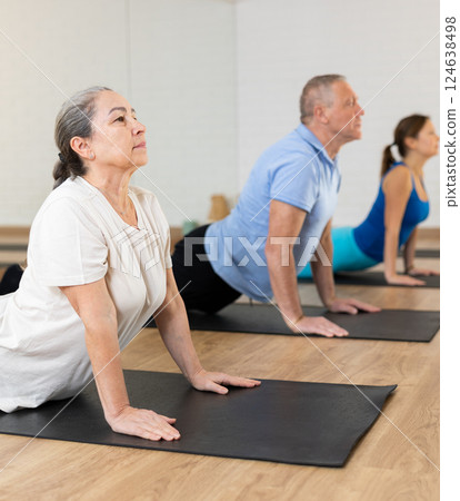 Elderly woman practicing pilates on mat in gym area 124638498