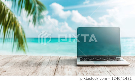 Laptop on wooden table by tropical beach, palm leaves in view 124641481