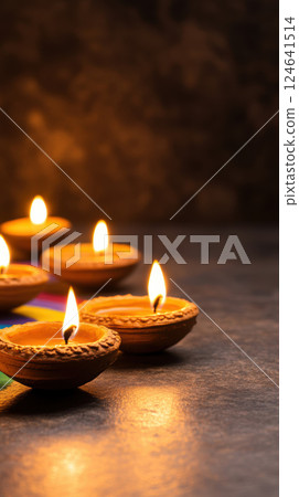 Traditional clay diyas with warm glow on dark surface 124641514