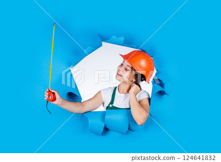 teen girl builder in protective helmet use tape measuer, size 124641832