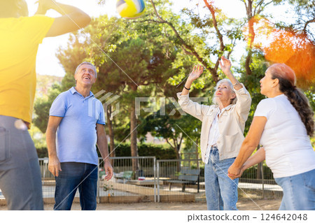 Joyful multiracial group of mature adult people playing volleyball game outdoors Joyful multiracial group of mature adult people playing volleyball game outdoors 124642048