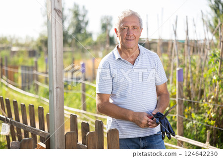 Portrait of an elderly owner of village farm with tools in his hands 124642230