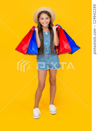 happy teen child with shopping bags on yellow background. summer sales 124642289