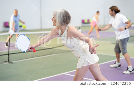 Mature woman playing doubles pickleball game, healthy lifestyle concept 124642290