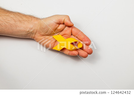 Supporting cancer awareness with a yellow ribbon symbol of hope and solidarity Supporting cancer awareness with a yellow ribbon symbol of hope and solidarity 124642432