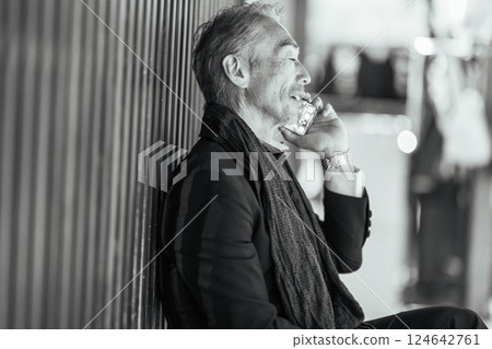 A gentleman sitting on the phone at a restaurant at night 124642761