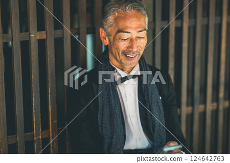 晚上,一位先生坐在餐廳裡打電話 晚上,一位先生坐在餐廳裡打電話 124642763