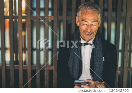 A gentleman sitting on the phone at a restaurant at night 124642765