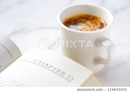 一個人一邊喝咖啡一邊悠閒地閱讀平裝書的圖像。 一個人一邊喝咖啡一邊悠閒地閱讀平裝書的圖像。 124643035