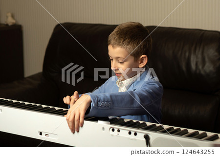 Young boy in blue blazer adjusting the piano Young boy in blue blazer adjusting the piano 124643255