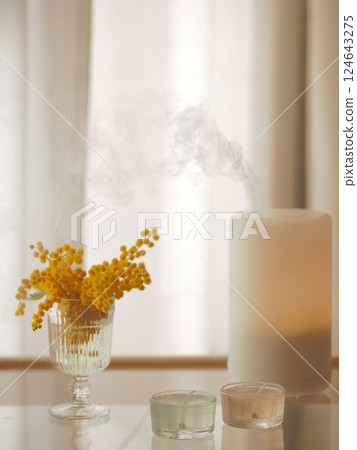 Mimosa flowers and aroma candles on a side table Mimosa flowers and aroma candles on a side table 124643275