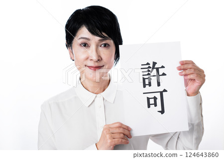 一位快樂的中年婦女拿著一張寫著「許可」的卡片 一位快樂的中年婦女拿著一張寫著「許可」的卡片 124643860