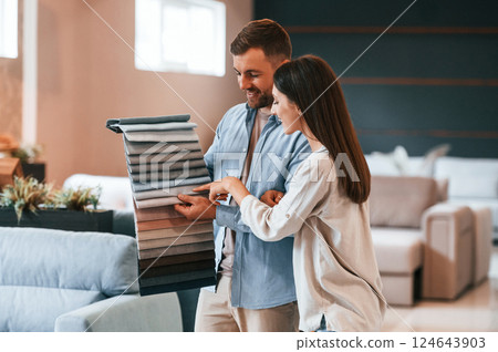 Looking for right color. Couple choosing the sofa and bed in the store 124643903
