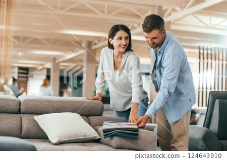 Big choice of colors and materials. Couple choosing the sofa and bed in the store Big choice of colors and materials. Couple choosing the sofa and bed in the store 124643910