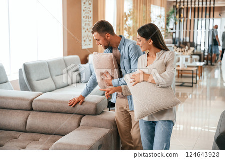 Having fun by choosing the sofa. Couple is in the store Having fun by choosing the sofa. Couple is in the store 124643928