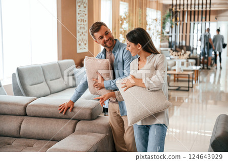 Beautiful product. Couple choosing the sofa and bed in the store 124643929
