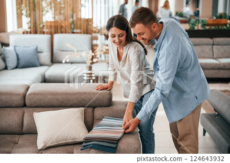 Beautiful product. Couple choosing the sofa and bed in the store 124643932