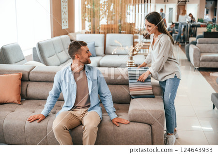Beautiful product. Couple choosing the sofa and bed in the store 124643933