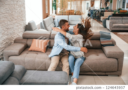 Sitting and relaxing. Couple choosing the sofa and bed in the store 124643937
