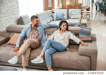 Sitting and relaxing. Couple choosing the sofa and bed in the store Sitting and relaxing. Couple choosing the sofa and bed in the store 124643938