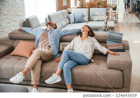 Sitting and relaxing. Couple choosing the sofa and bed in the store 124643939