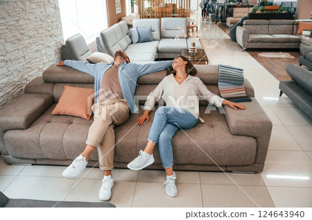 Sitting and relaxing. Couple choosing the sofa and bed in the store Sitting and relaxing. Couple choosing the sofa and bed in the store 124643940