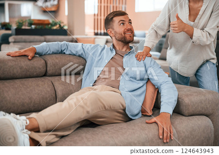 Having fun. Couple choosing the sofa and bed in the store 124643943