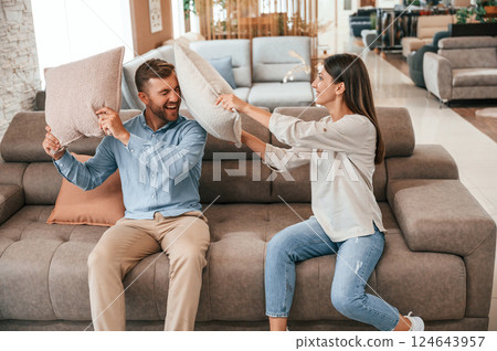 Having fun with pillows. Couple choosing the sofa and bed in the store Having fun with pillows. Couple choosing the sofa and bed in the store 124643957