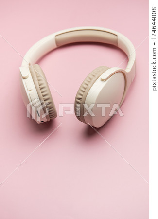 Modern wireless headphones lying on pink background 124644008