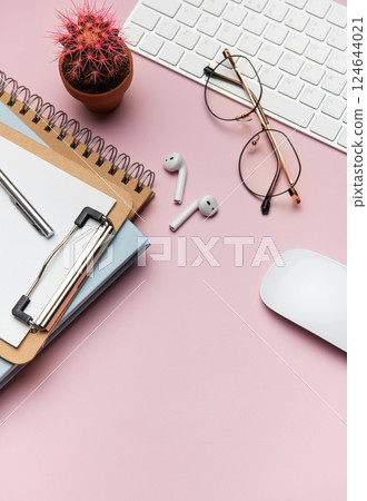 Workspace organizing accessories on pink table with plant and keyboard 124644021