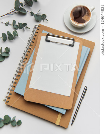 Clipboard with blank paper, notebooks and coffee cup on white table 124644022