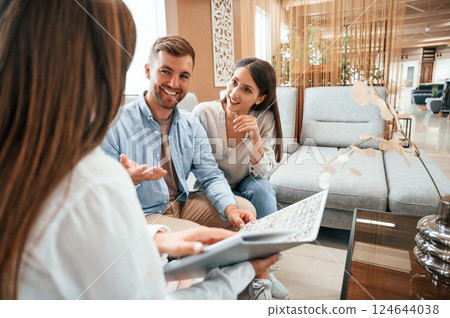 Woman helping couple with choosing the sofa and bed in the store 124644038