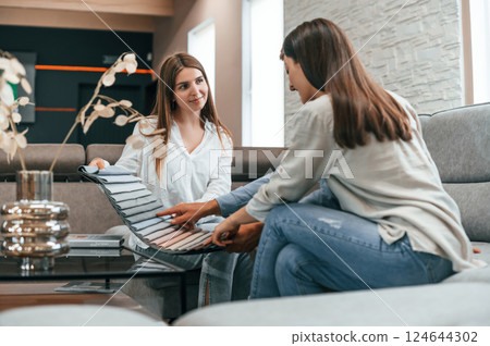 Sitting together. Woman helping couple with choosing the sofa and bed in the store 124644302