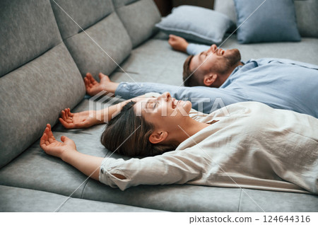 Laying down together. Couple choosing the sofa and bed in the store Laying down together. Couple choosing the sofa and bed in the store 124644316