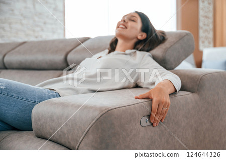 Trying automatic switches. Woman is visiting bed store. Looking for comfortable sofa Trying automatic switches. Woman is visiting bed store. Looking for comfortable sofa 124644326