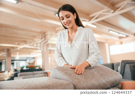 Touching the smooth surface. Woman is visiting bed store. Looking for comfortable sofa Touching the smooth surface. Woman is visiting bed store. Looking for comfortable sofa 124644337