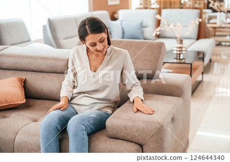 Sitting and relaxing. Woman is visiting bed store. Looking for comfortable sofa 124644340