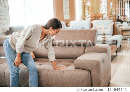 Sitting and relaxing. Woman is visiting bed store. Looking for comfortable sofa 124644341
