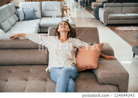 Sitting and relaxing. Woman is visiting bed store. Looking for comfortable sofa 124644343