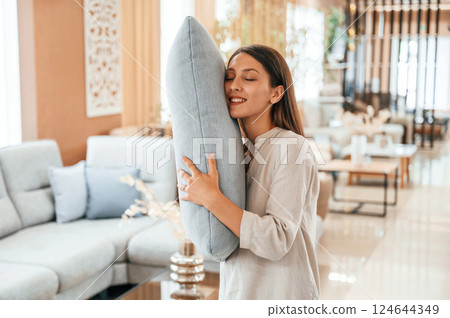 Embracing the pillow. Woman is visiting bed store. Looking for comfortable sofa 124644349