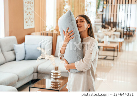 Embracing the pillow. Woman is visiting bed store. Looking for comfortable sofa 124644351