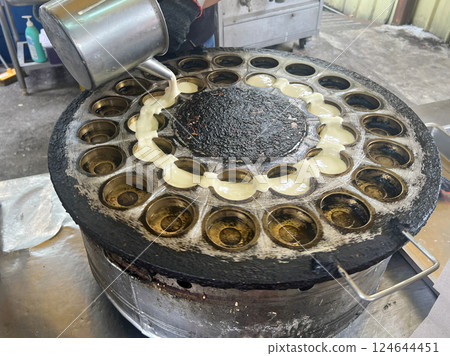拍攝攤販熟練的將麵糊倒入模具中製作車輪餅 拍攝攤販熟練的將麵糊倒入模具中製作車輪餅 124644451